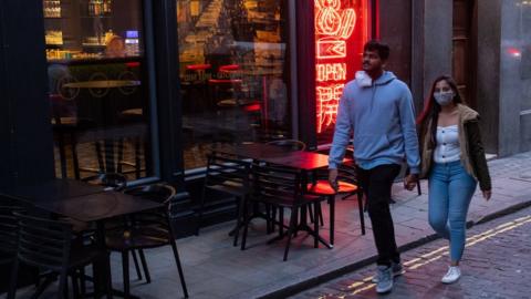 Couple walking past empty London restaurant