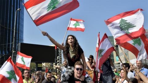 Anti-government protesters hold up Lebanese flags in Forn el-Chebbak, Beirut, Lebanon (21 October 2019)