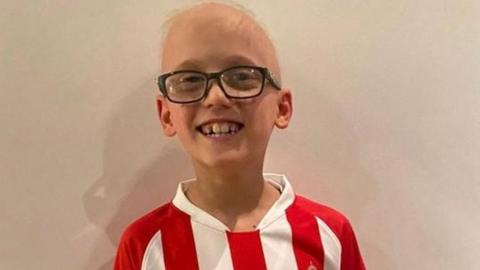 A boy smiles while wearing a Sunderland shirt