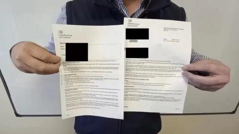Man holding up a letter from the HM Revenue and Customs