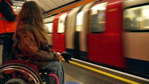 A wheelchair user waits for a tube train