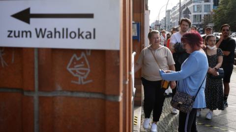 People waits oustide a polling station to vote in the German general elections in Berlin, Germany, 26 September 2021