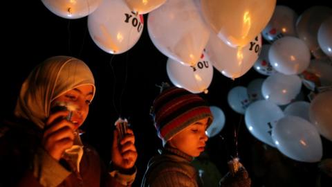 Children carry balloons before releasing them towards Damascus from the rebel-held suburb of Jobar, 30 December