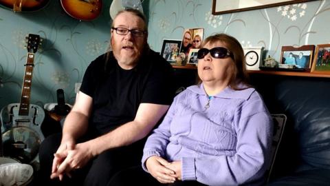 Judith Mason, 57, and her partner and carer Ron Roberts, 55, discuss her struggles at their Bootle home
