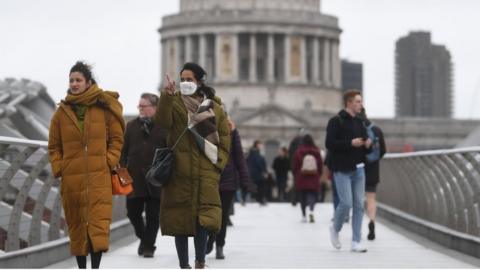 People in masks walking in London