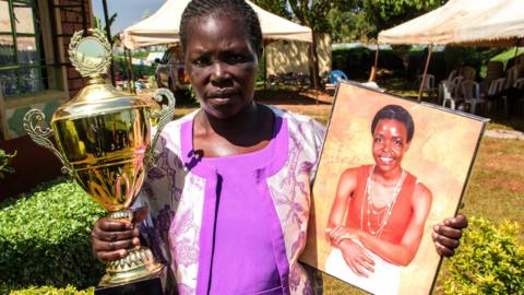 Dinah Tirop with a trophy and a picture of her daughter Agnes