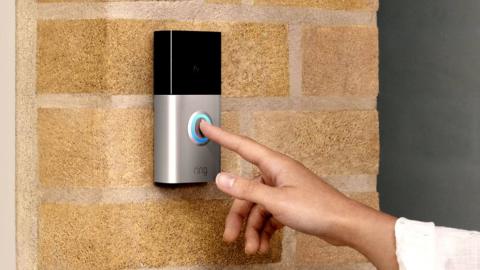 A finger pushing the button on a ring doorbell