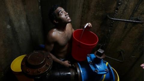 Locals collect water from an underground water main pipeline in Caracas, Venezuela March 12, 2019.
