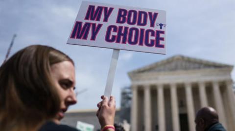 A women holds a sign reading "My body my choice"