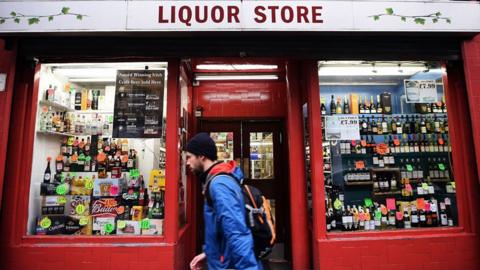 A pedestrian walks past an off-license store in Glasgow