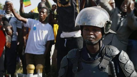 Scene from Bamako as people celebrate, while a police officer watches