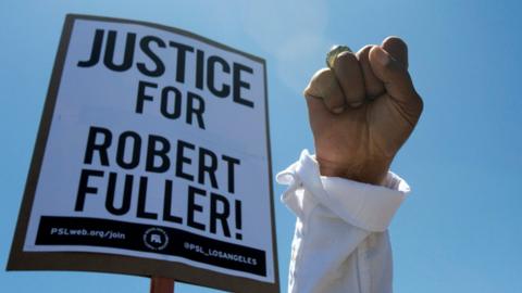 A sign reads 'Justice for Robert Fuller'