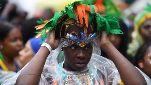 A dancer adjusting her costume at the Notting Hill carnival