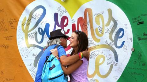 People hug in front of a heart painted on the Pulse nightclub in Orlando, Fla., Friday, Sept. 30. 2016.