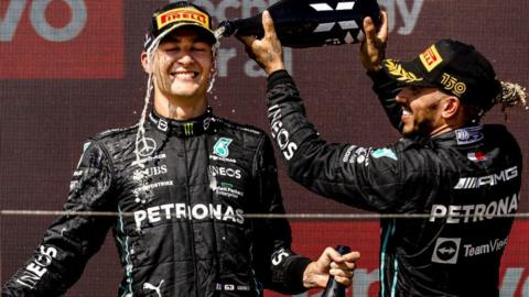 Lewis Hamilton pours champagne over team-mate George Russell on the podium