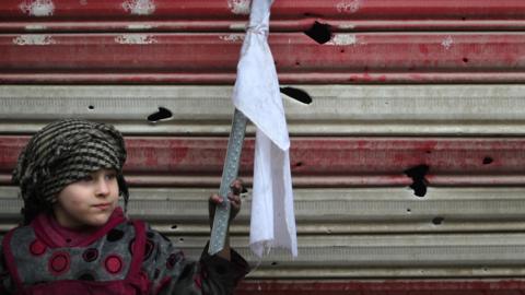 An Iraqi girl holding a white flag stands on a street with her mother as Iraqi security forces secure Mosul's Al-Dawasa neighbourhood on 13 March