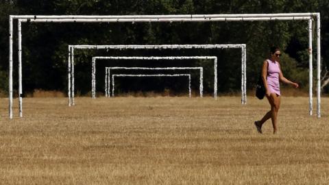 Woman walking across Hackney Marshes as a drought is declared in parts of England