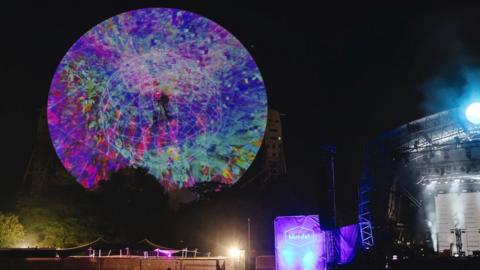 The Lovell radio telescope at Jodrell Bank lit with scientific data for the Bluedot festival