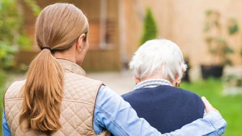 Young woman supporting elderly woman