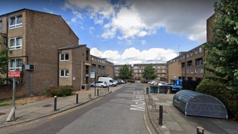 Google StreetView image of brick housing blocks, a car park and bike storage on McNeil Road.