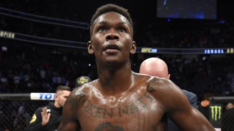 Israel Adesanya celebrates after defending his middleweight title against Yoel Romero at UFC 248