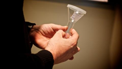 A man's hands holding a sperm sample tube