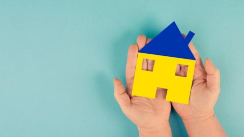 Blue and yellow house in hands