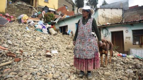 A woman looks at her house that was affected by landslides caused by rains that buried homes and left fatalities, in Achocalla, Bolivia February 17, 2024.