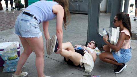 A girl feels sick from high temperatures as she waits outside the stadium for a concert, following the death of a fan due to the heat during the concert of Taylor Swift, in Rio de Janeiro, Brazil, November 18, 2023.