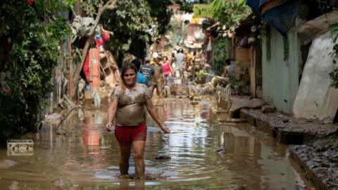 A woman wades through muddy floodwater following Typhoon Vamco, in San Mateo, Rizal province