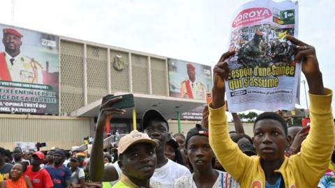 A man holds up a newspaper at a concert marking the first anniversary of the coup in Guinea, on September 5, 2022.