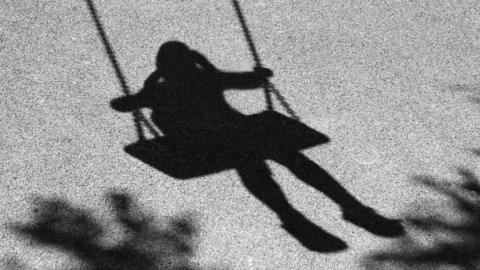 Single girl in shadow on a swing