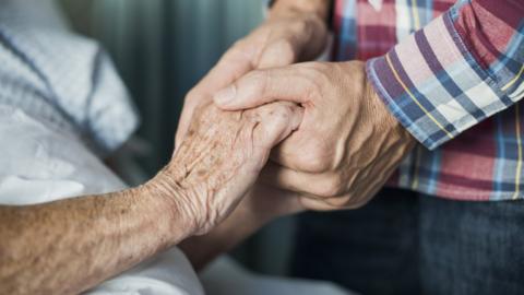 A son holding his mother's hand