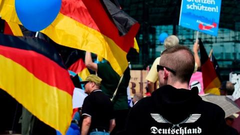 Demonstrators holding AfD and German flags gather at a protest in Berlin in 2018