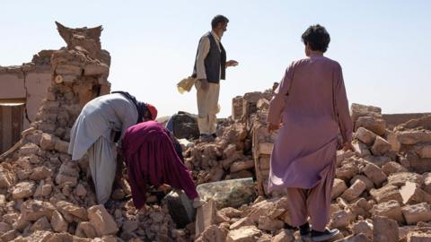 Afghan men comb through the rubble in the aftermath of the earthquake in Herat