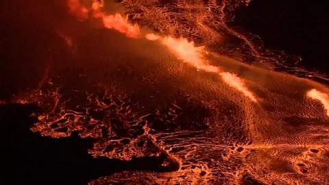 Lava spewing over a mountain surrounded by land