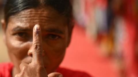 A woman shows her inked finger after casting her ballot at a polling station as voting starts in the first phase of India's general election at the Dugeli village of Dantewada district, in the country's Chhattisgarh state on April 19, 2024.