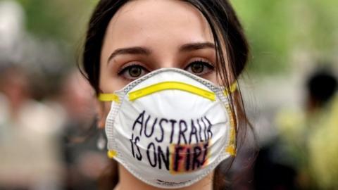 A woman wearing a mask saying Australia is on Fire at a climate protest