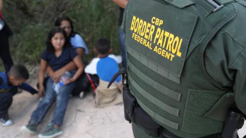 Central American asylum seekers wait as US Border Patrol agents take them into custody near McAllen, Texas, on 12 June 2018