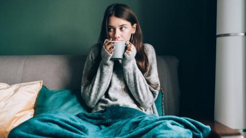 Woman with cup of tea with blanket