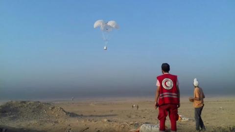 A worker from WFP's partner, the Syrian Arab Red Crescent, prepares to collect air-dropped cargo outside Deir al-Zour