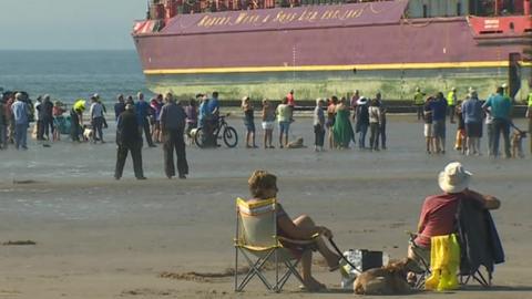 people sat watching barge at Black Rock beach