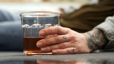 A person holding a glass of whisky