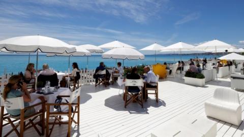 Customers enjoy a lunch on the terrace of a beach restaurant in Nice, France