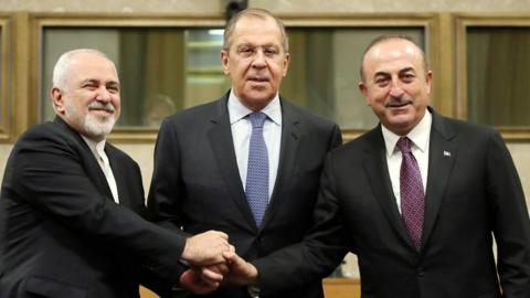 Russian Foreign Minister Sergei Lavrov (C), Turkish Foreign Minister Mevlut Cavusoglu (R) and Iranian Foreign Minister Mohammad Javad Zarif (L) shake hands as they attend a news conference after talks on forming a constitutional committee in Syria, at the United Nations in Geneva, Switzerland, on 18 December 2018