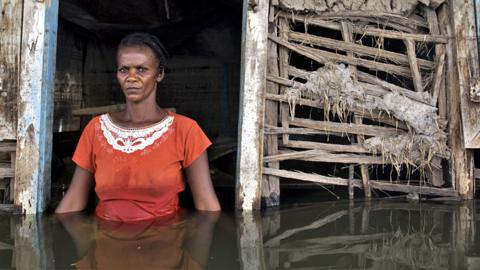 A woman stands in the doorway of her flooded home in Savanne Desole on the outskirts of the city of Gonaives, Haiti