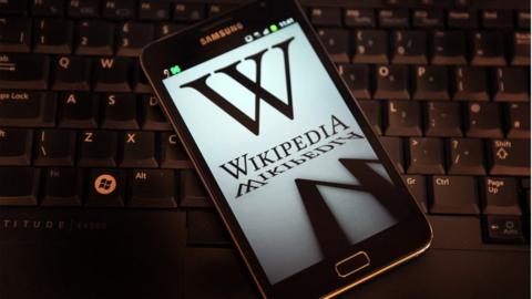 A mobile device shows Wikipedia's front page displaying a darkened logo on 18 January, 2012