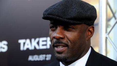 Idris Elba wearing a flat cap