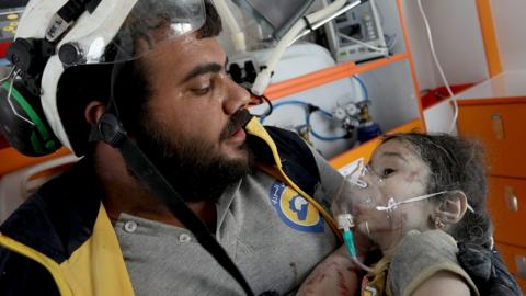 A rescue worker holds a child pulled from the rubble of a destroyed building after an air strike on a market place in the opposition-held town of Maarat al-Numan, Syria (22 July 2019)