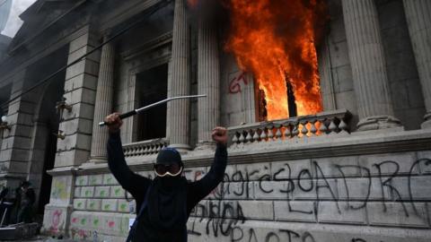 Demonstrators gesture after setting on fire an office of the Congress building during a protest demanding the resignation of President Alejandro Giammattei, in Guatemala City on November 21, 2020